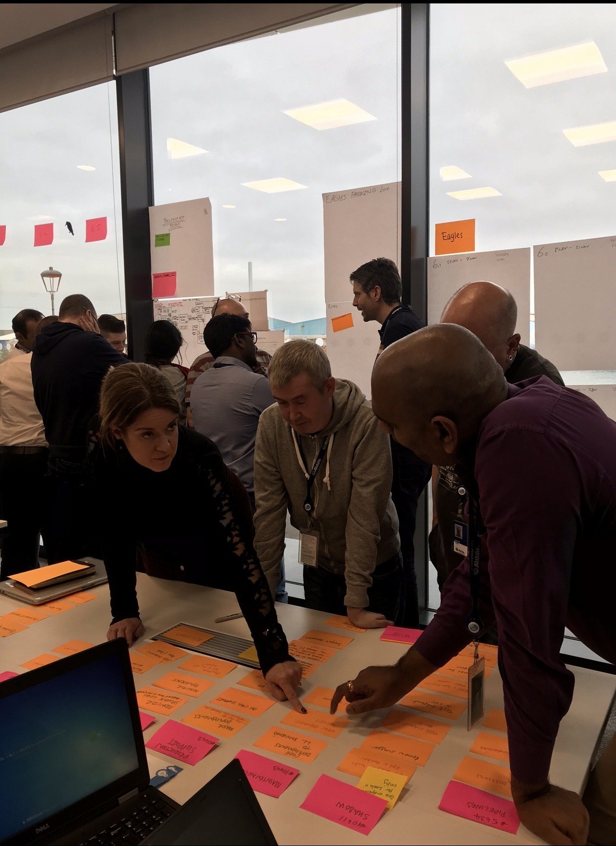 A cross-functional group mapping work with sticky notes during a workshop